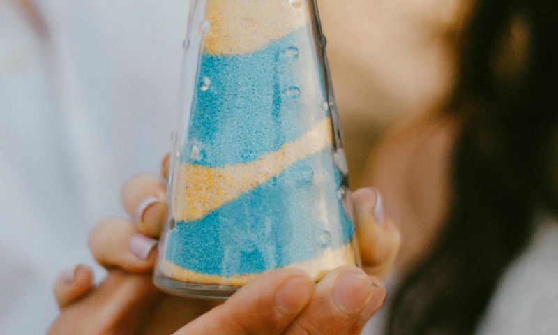 Persone reggono un vasetto di sabbia azzurra e gialla