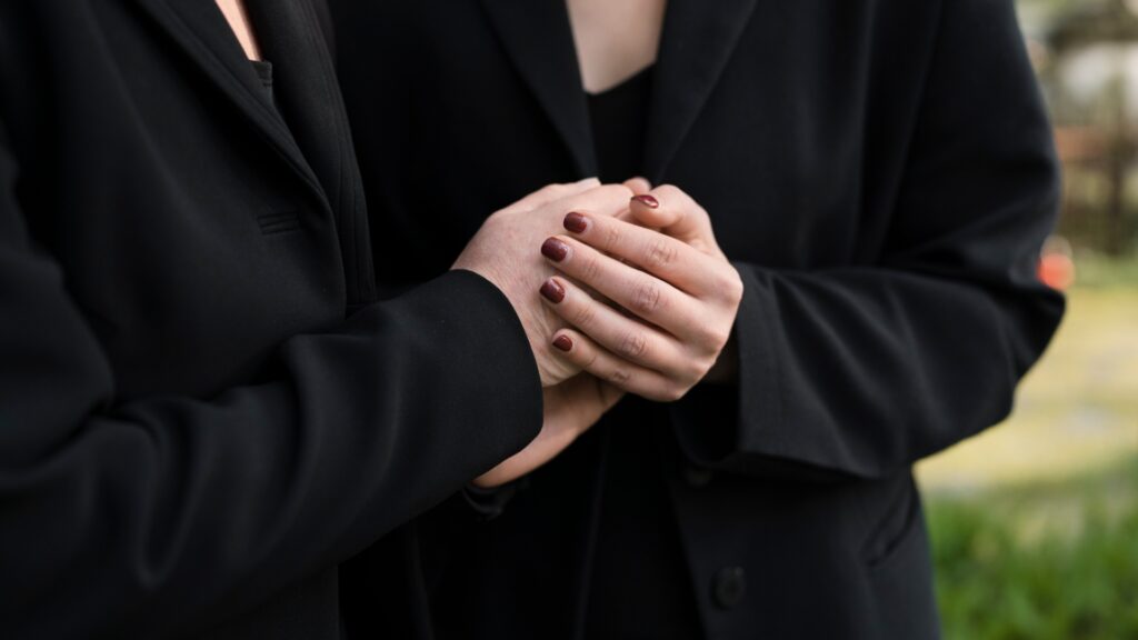 Due donne si stringono le mani a un funerale