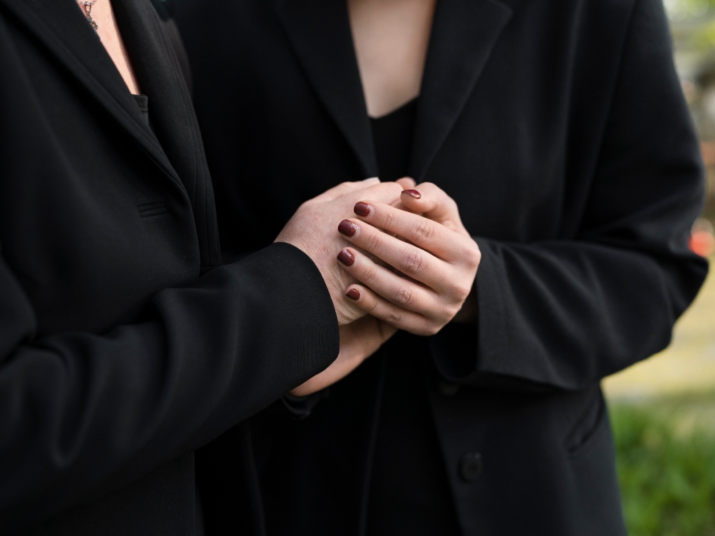musica funerale collegno laico Due donne si stringono per mano a un funerale