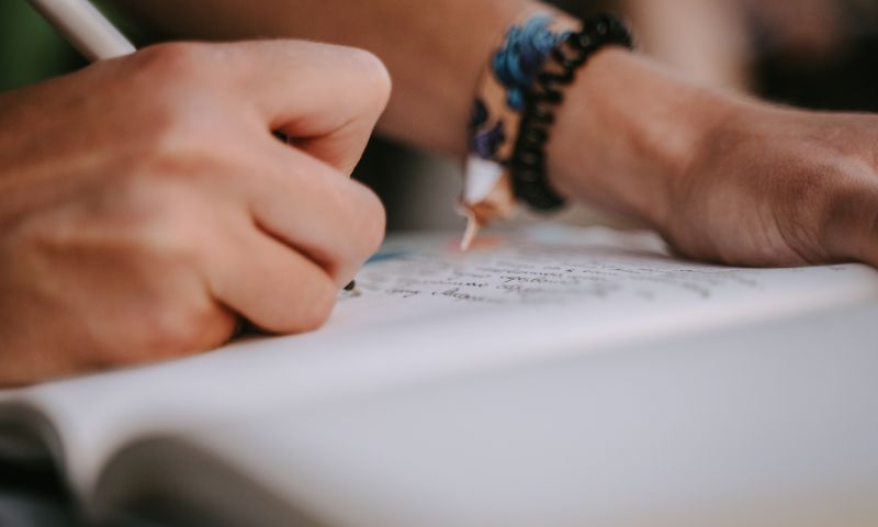 Mani maschili scrivono una poesia per l'anniversario di matrimonio con carta e penna