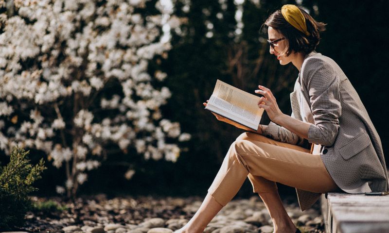 Donna seduta su un muretto legge delle letture per il matrimonio civile